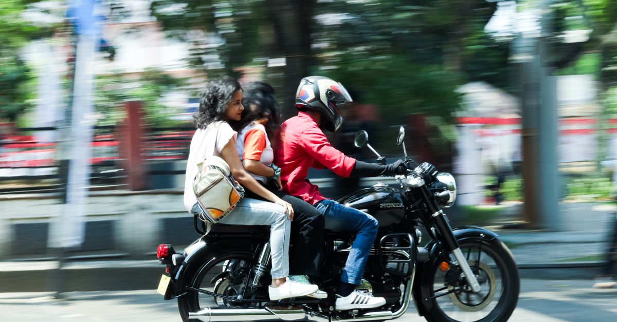 Three people riding a motorcycle on Kochi streets, showcasing urban movement and lifestyle.