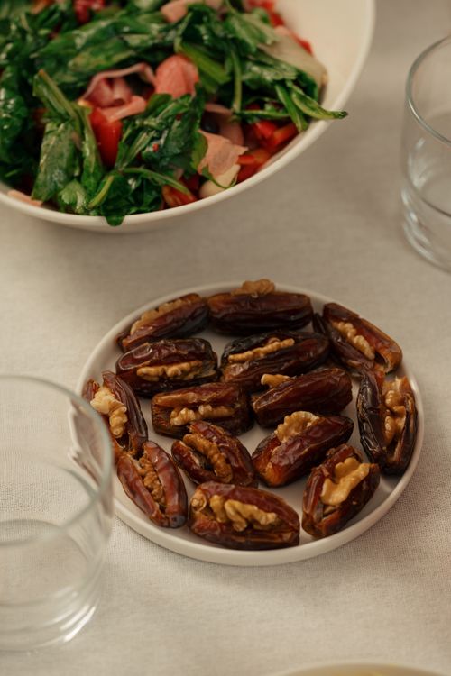 Free A festive dining table featuring dates filled with walnuts and a fresh salad bowl, ideal for cultural celebrations. Stock Photo