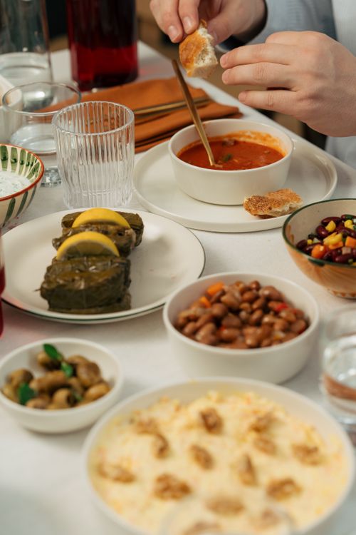 Free Close-up of diverse Mediterranean dishes and hands serving soup, perfect for home-cooking ideas. Stock Photo