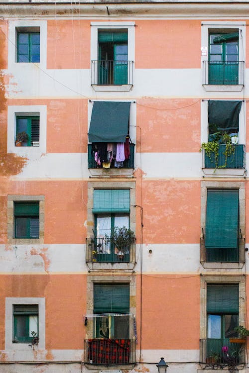 A pink and orange building with clothes hanging on the windows