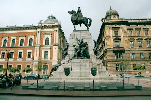 A statue of a man on horseback in front of buildings