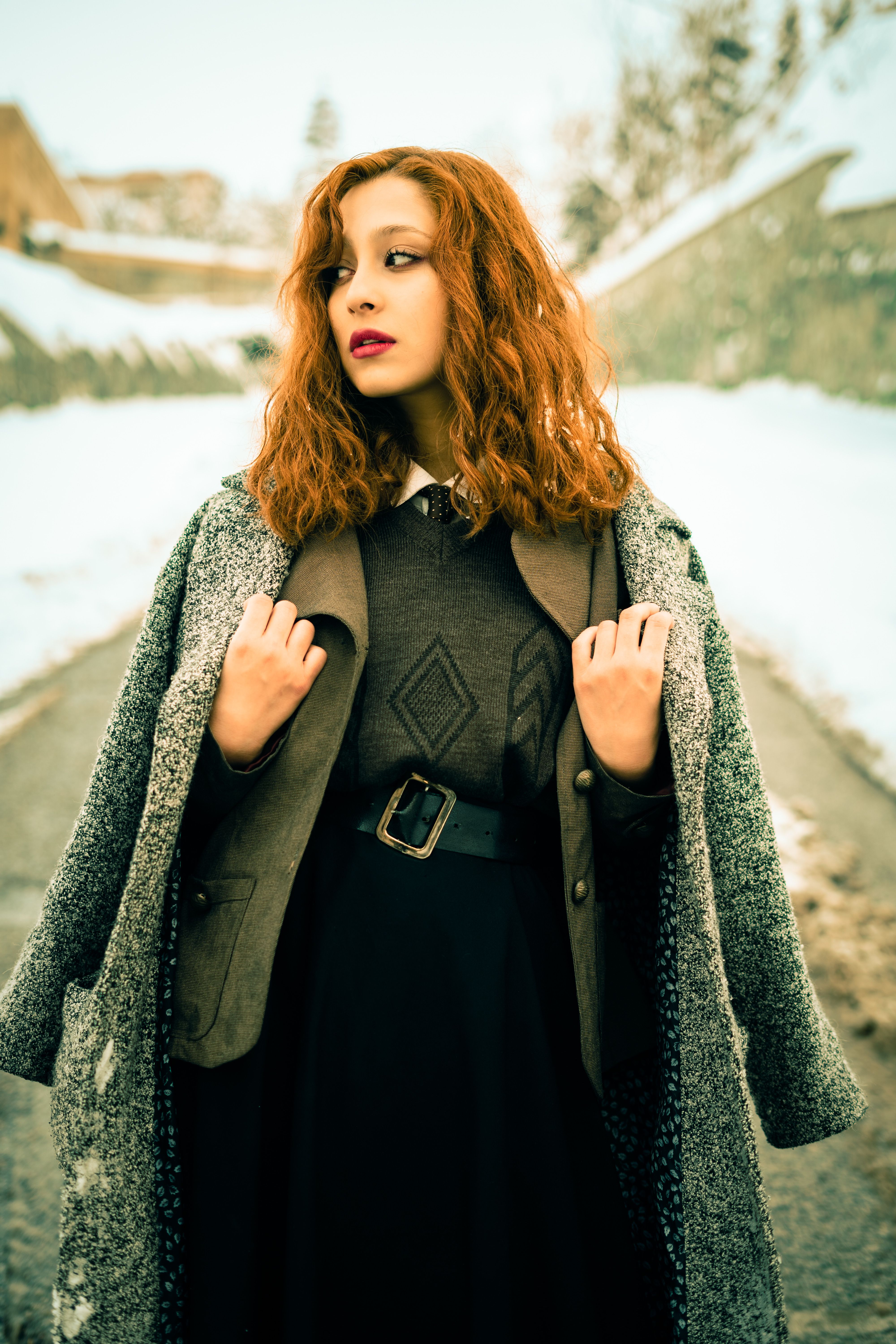 Woman in black peacoat with pleated midi skirt