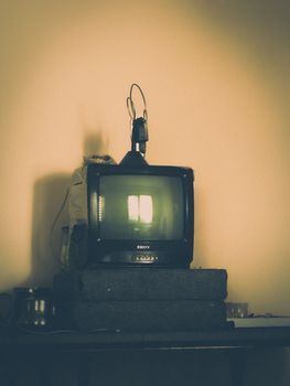 Retro CRT television with antenna on a rustic table in a softly lit room.