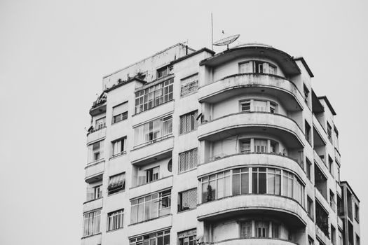 Monochrome photo of a high-rise apartment building with curved balconies and windows.