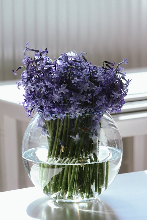 A vase of purple flowers in a glass bowl
