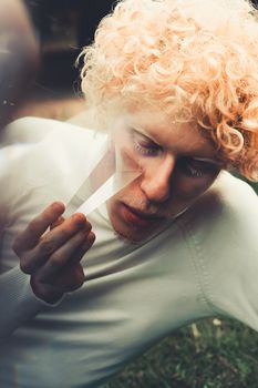 一个卷曲金发男人的特写肖像，在户外手持棱镜，创造出梦幻般的效果