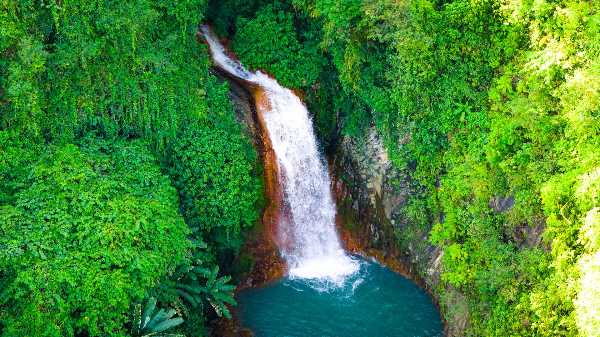A stunning aerial shot capturing a lush green landscape and vibrant waterfall in Cebu City, Philippines.