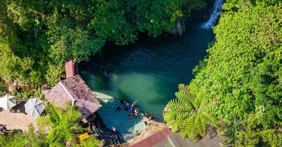 A panoramic view of the Lower Wli Waterfalls pool with tourists swimming