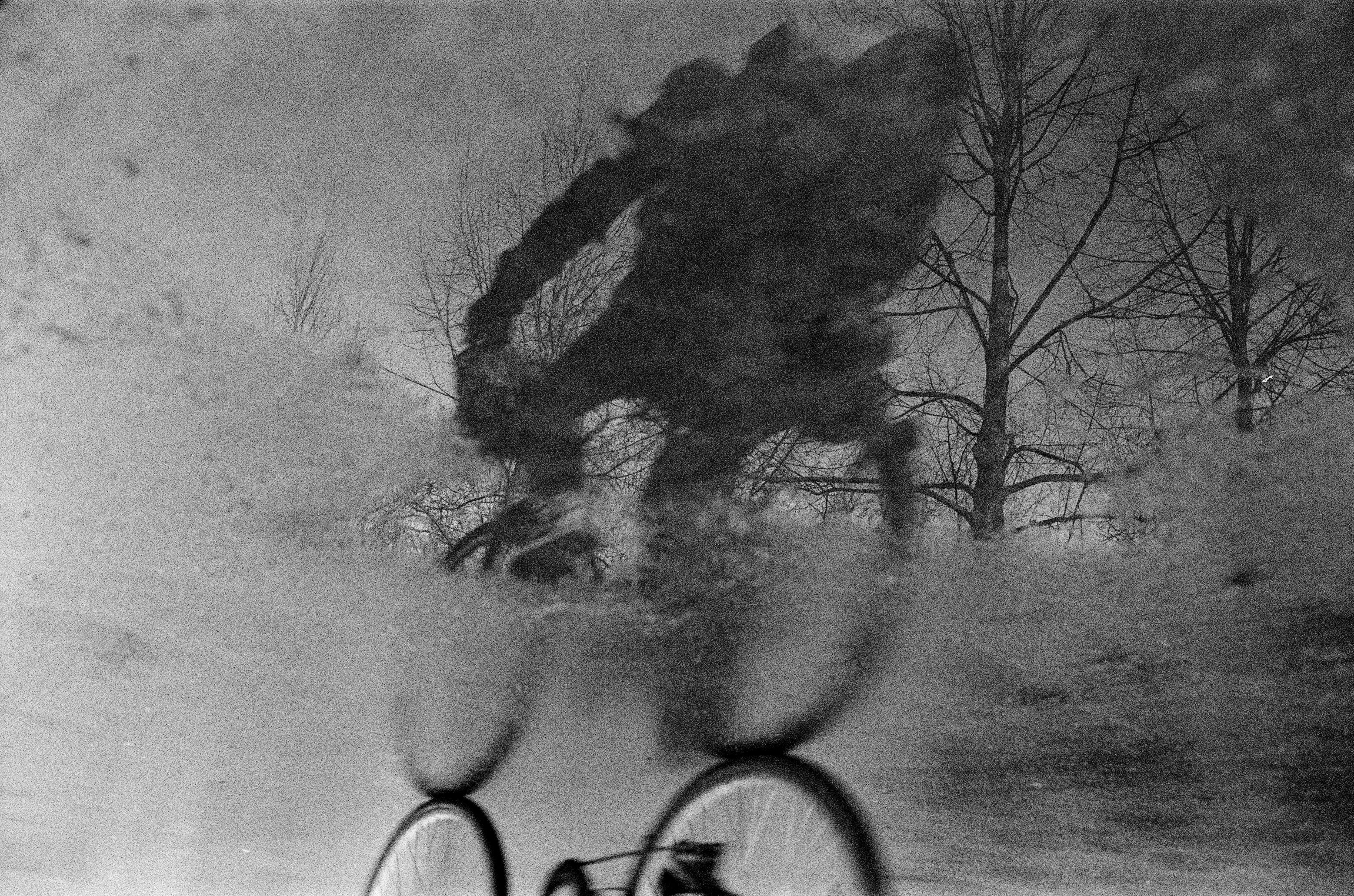 Black and white reflection of a cyclist riding through a wet surface in Nancy, France.