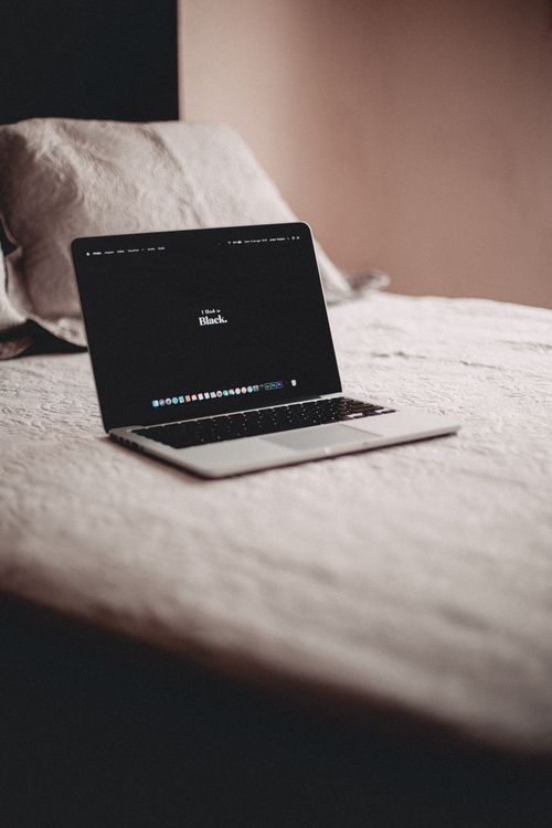 Free A sleek laptop on a cozy bed in a tranquil bedroom setting. Stock Photo
