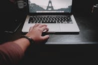 一个人正在木制桌子上用笔记本电脑远程工作，展现了现代技术