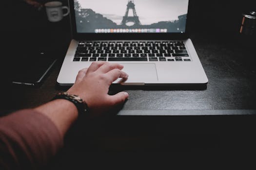 一个人正在木制桌子上用笔记本电脑远程工作，展现了现代技术