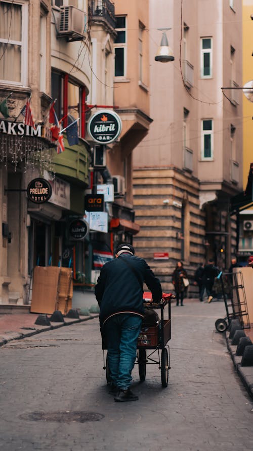 A man pushing a cart down a narrow street