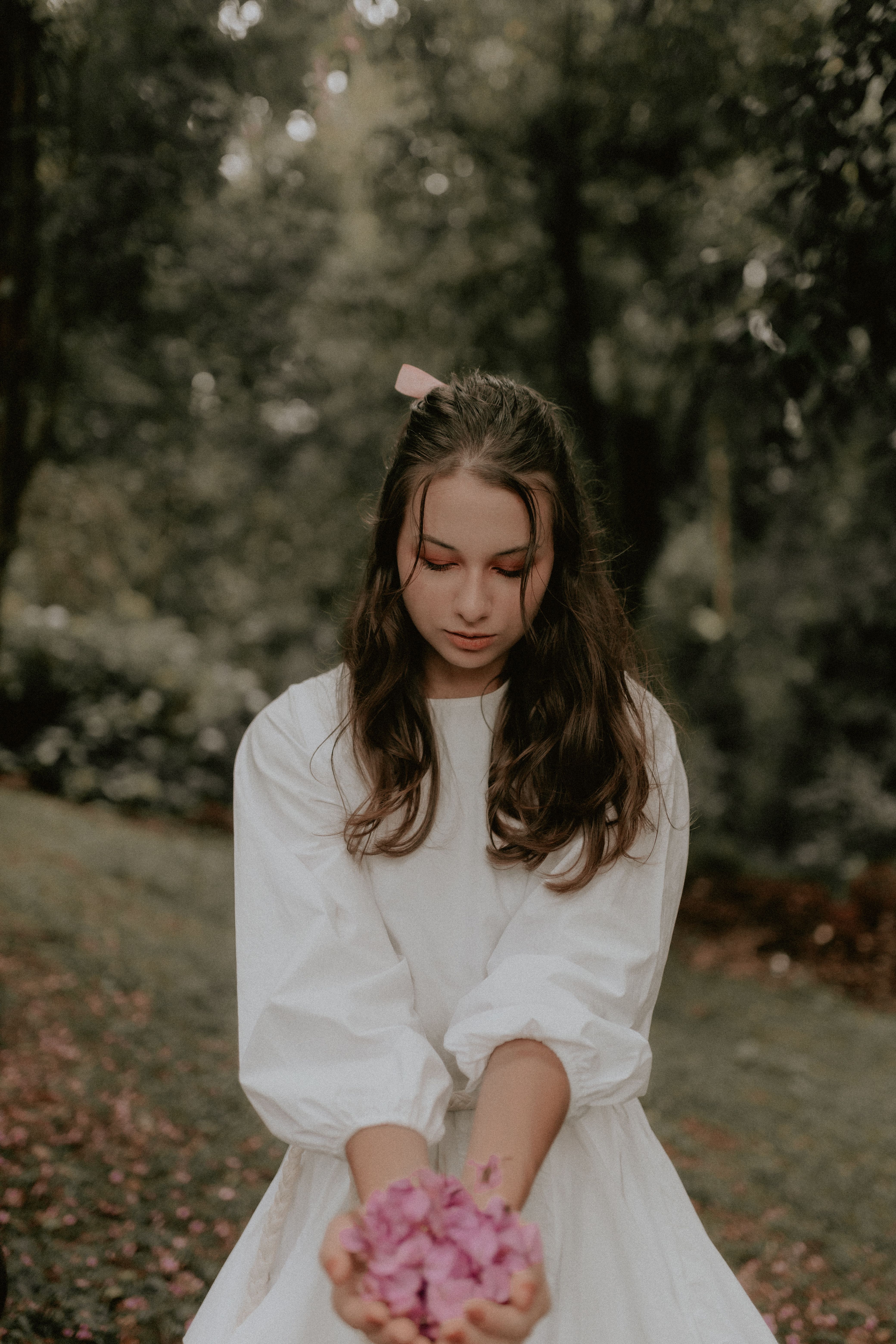 A Girl in a White Dress Standing Outside and Holding a Handful of ...