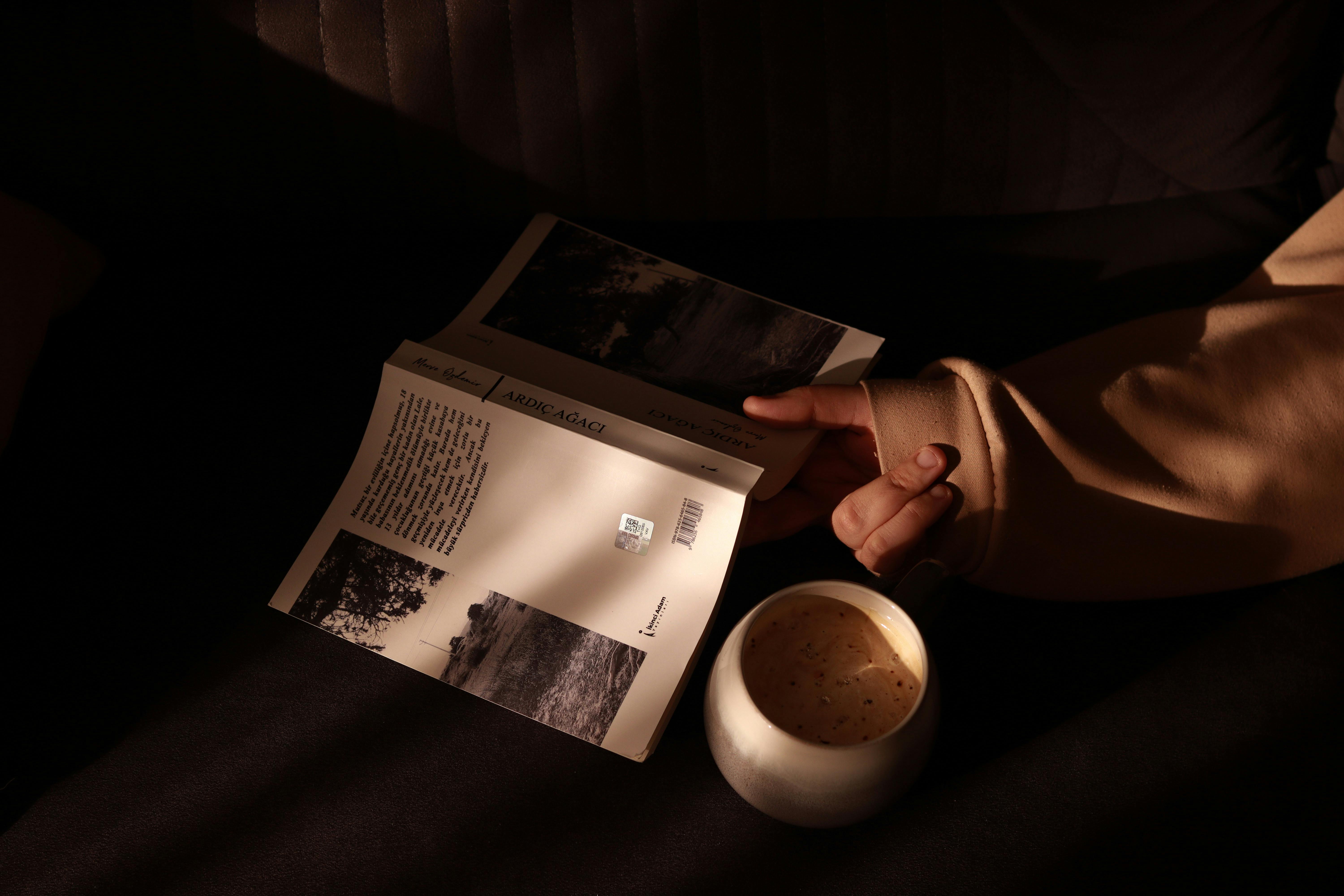 A warm, cozy scene featuring a person reading a book with a cup of coffee in soft, ambient light.