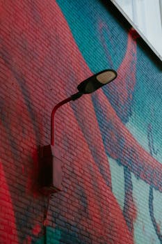 A vibrant mural featuring a street lamp on a brick wall in urban Rotterdam.