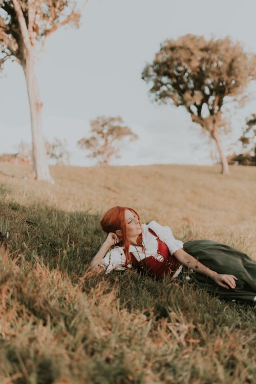 Free A woman laying down in a field with a dog Stock Photo