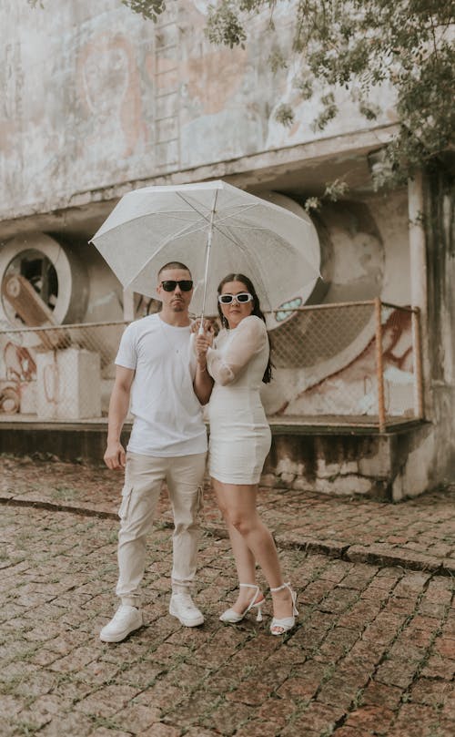 A couple posing for a photo under an umbrella