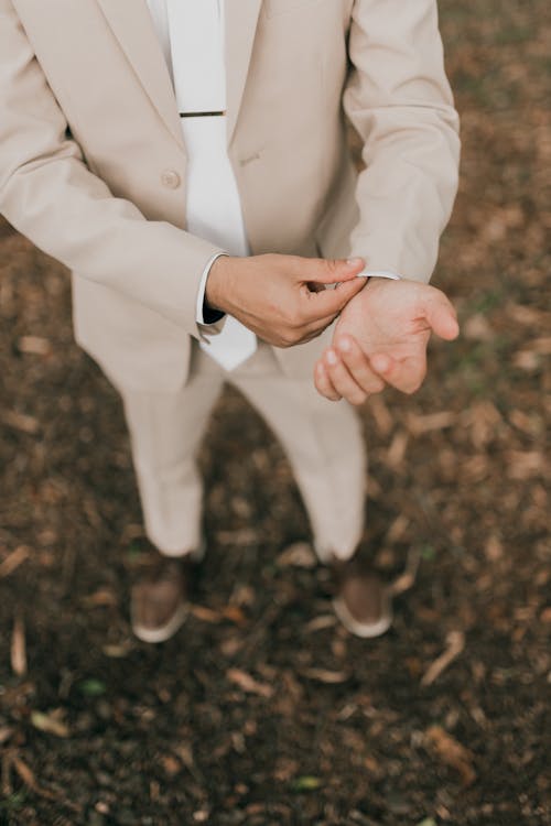 A man in a suit putting his hand on his wrist