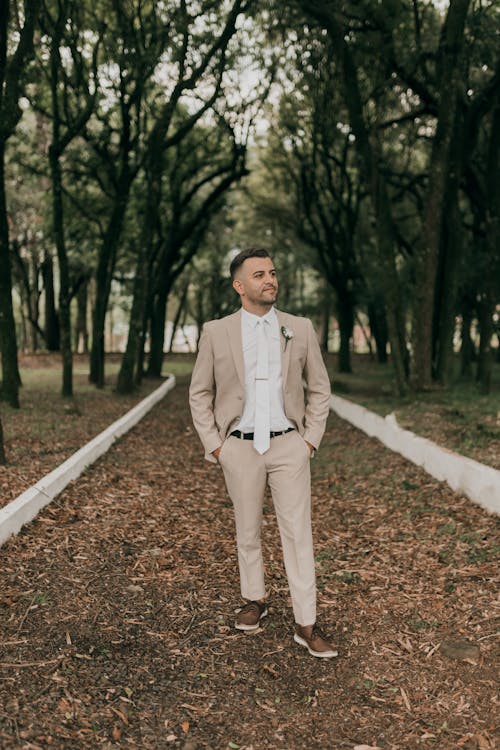 A man in a tan suit stands in the middle of a path