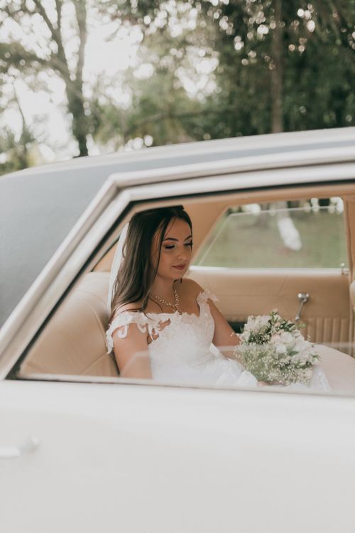 Free Beautiful bride sitting in wedding car holding bouquet, embodying elegance and anticipation. Stock Photo