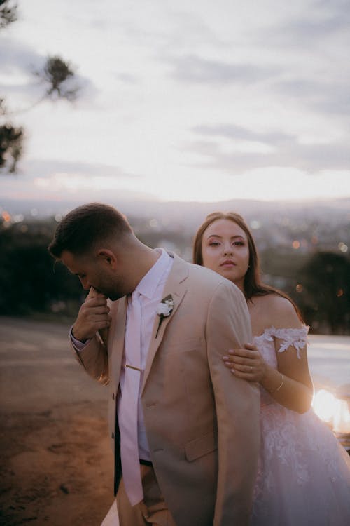 A bride and groom are standing in front of a sunset