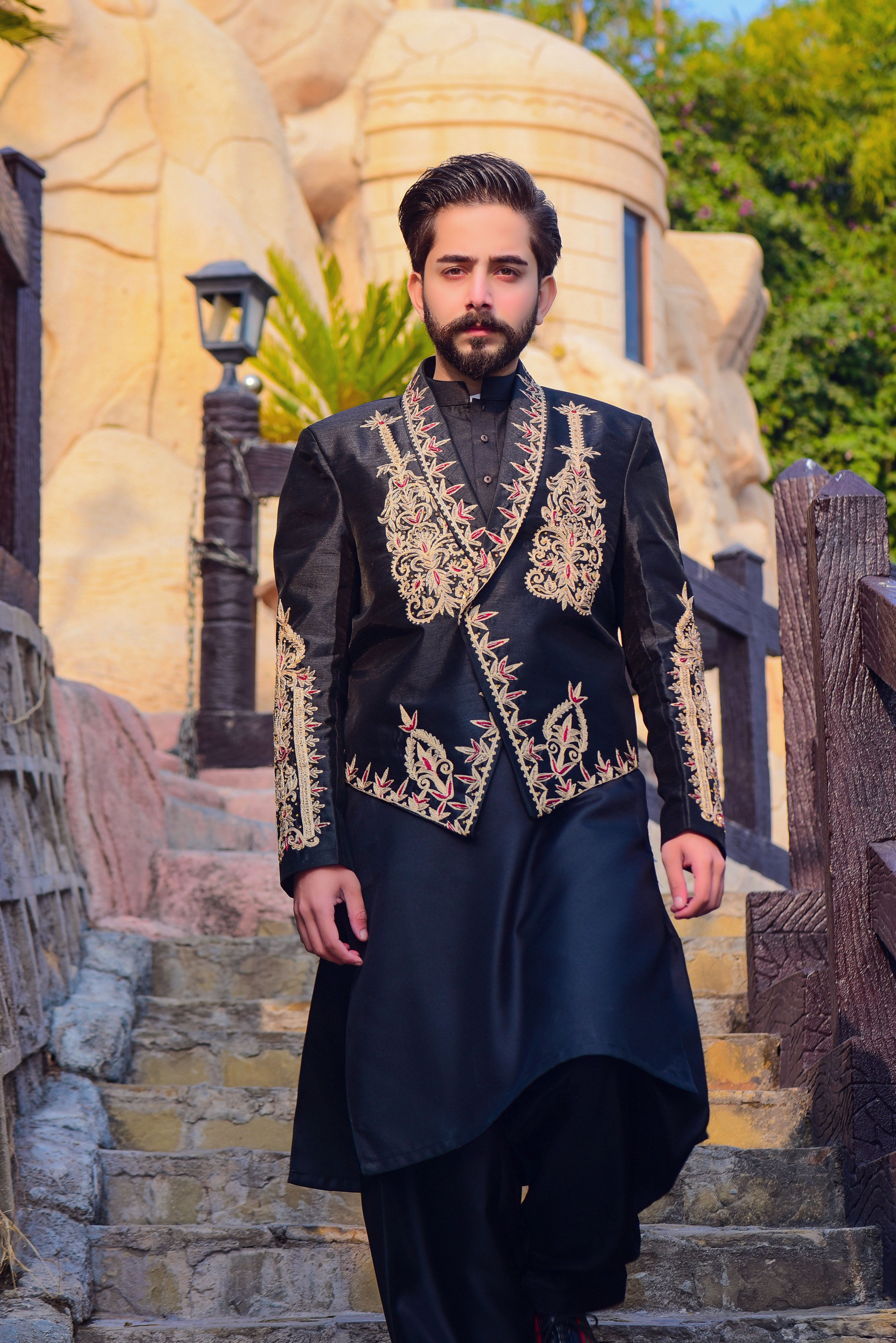 A stylish man in traditional embroidered attire descends stairs, showcasing elegance and cultural style.