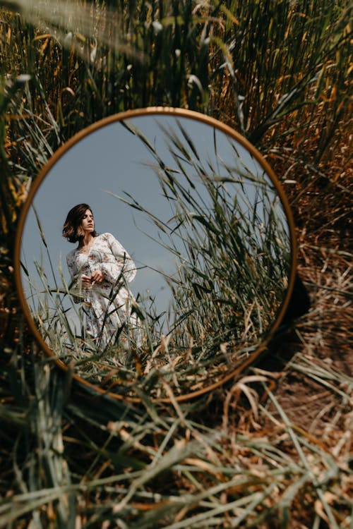 A woman in a white dress is standing in a field of tall grass