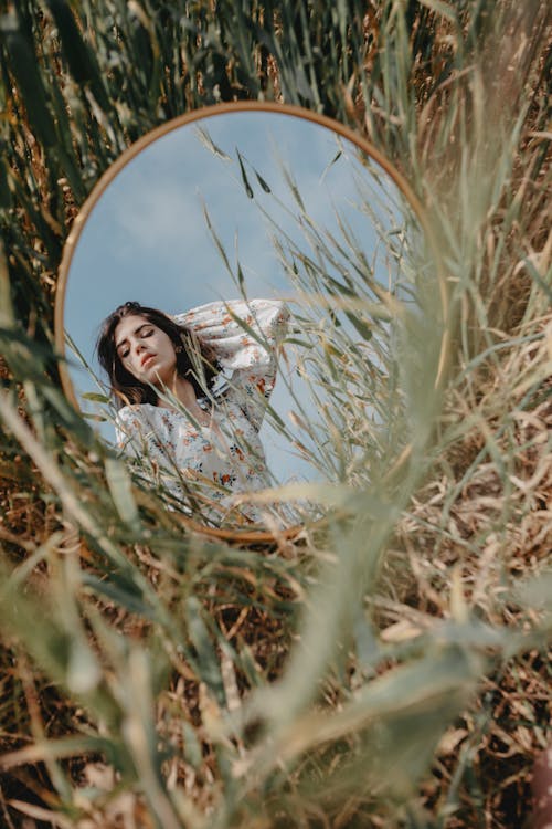 A woman in a field looking at a mirror