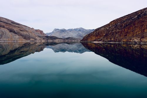 Free Serene lake with mountain reflections under a clear sky in a picturesque setting. Stock Photo