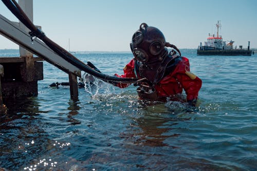 A diver in a scuba suit is standing in the water