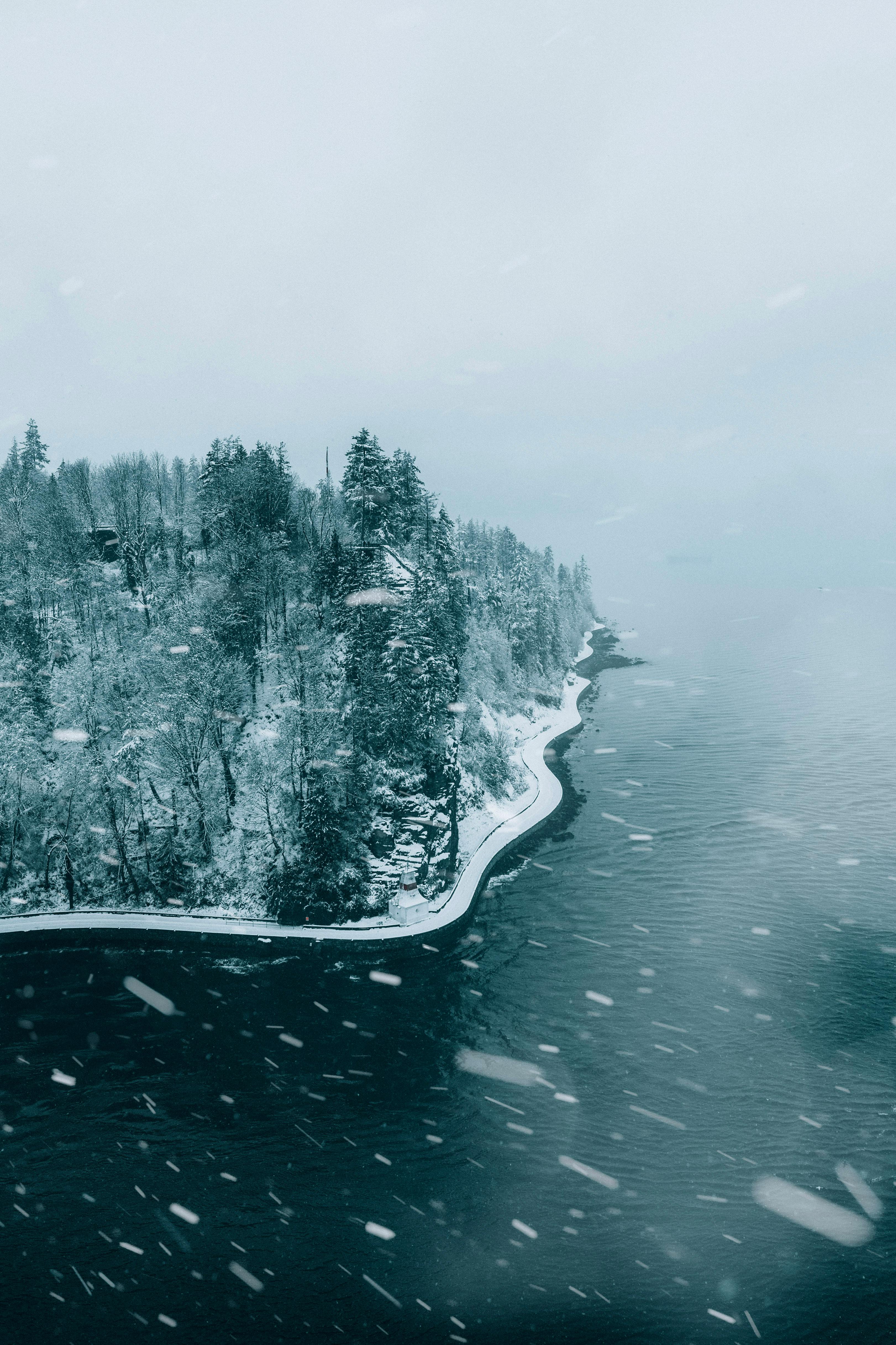 A serene aerial shot of a snow-covered island near Vancouver, BC, showcasing a winter landscape and calm sea.