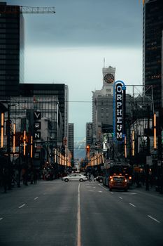 Vancouver urban street at night with neon lights and Orpheum sign, capturing city life.