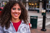 城市街道上站着一位妆容闪亮、留着卷发的幸福女人肖像