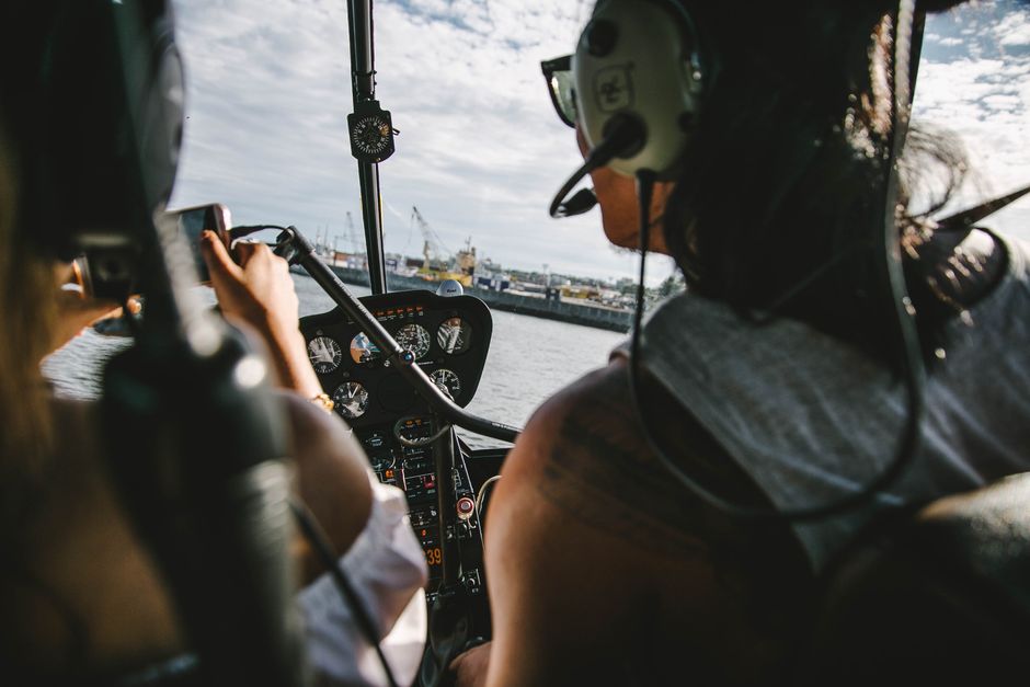 View from helicopter cockpit with pilots flying over the coast during daytime.