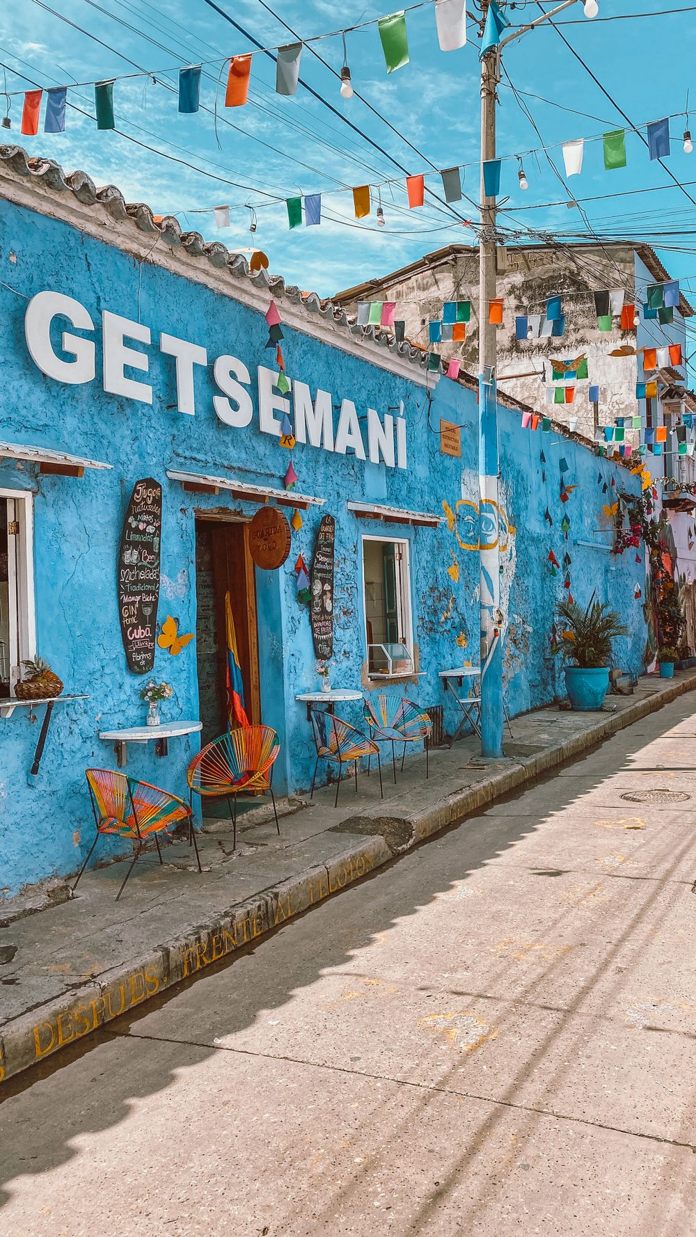 Fachada azul vibrante en Getsemaní con banderines de colores cruzando la calle