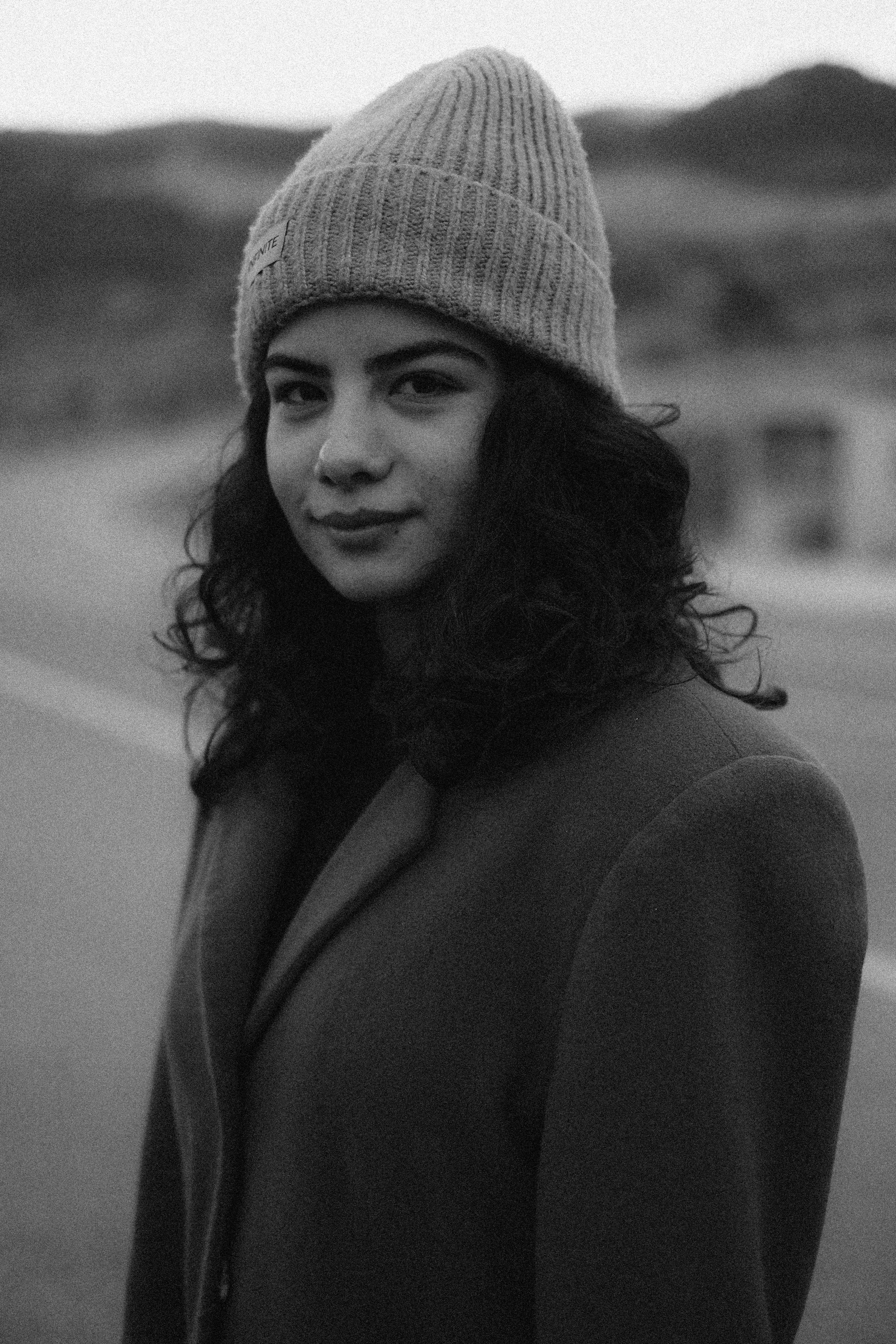 Portrait of a young woman in a beanie outdoors in a black and white photo.