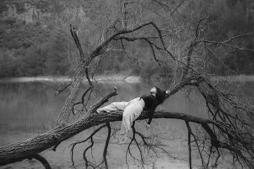Woman Lying on a Bent Tree Branch over a Lake 
