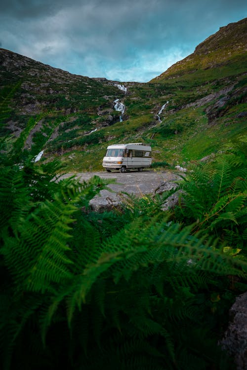A camper van parked in the mountains near a waterfall