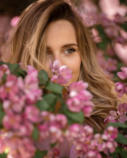Blonde Woman Face behind Pink Spring Blossoms