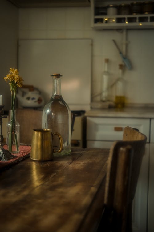 A kitchen table with a vase of flowers and a bottle of wine