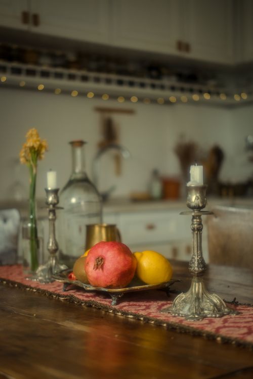 Free Warm still life of a kitchen table with pomegranate, lemon, and decorative candlesticks. Stock Photo