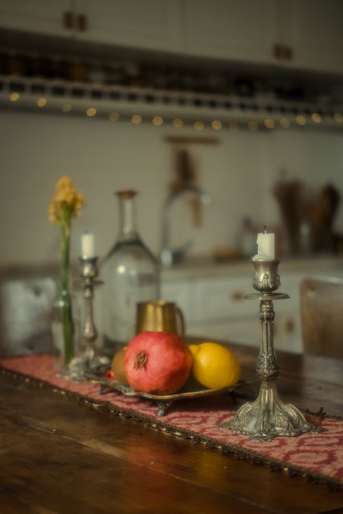 Free A cozy still life featuring candlesticks and fruit on a table in a warm kitchen setting. Stock Photo