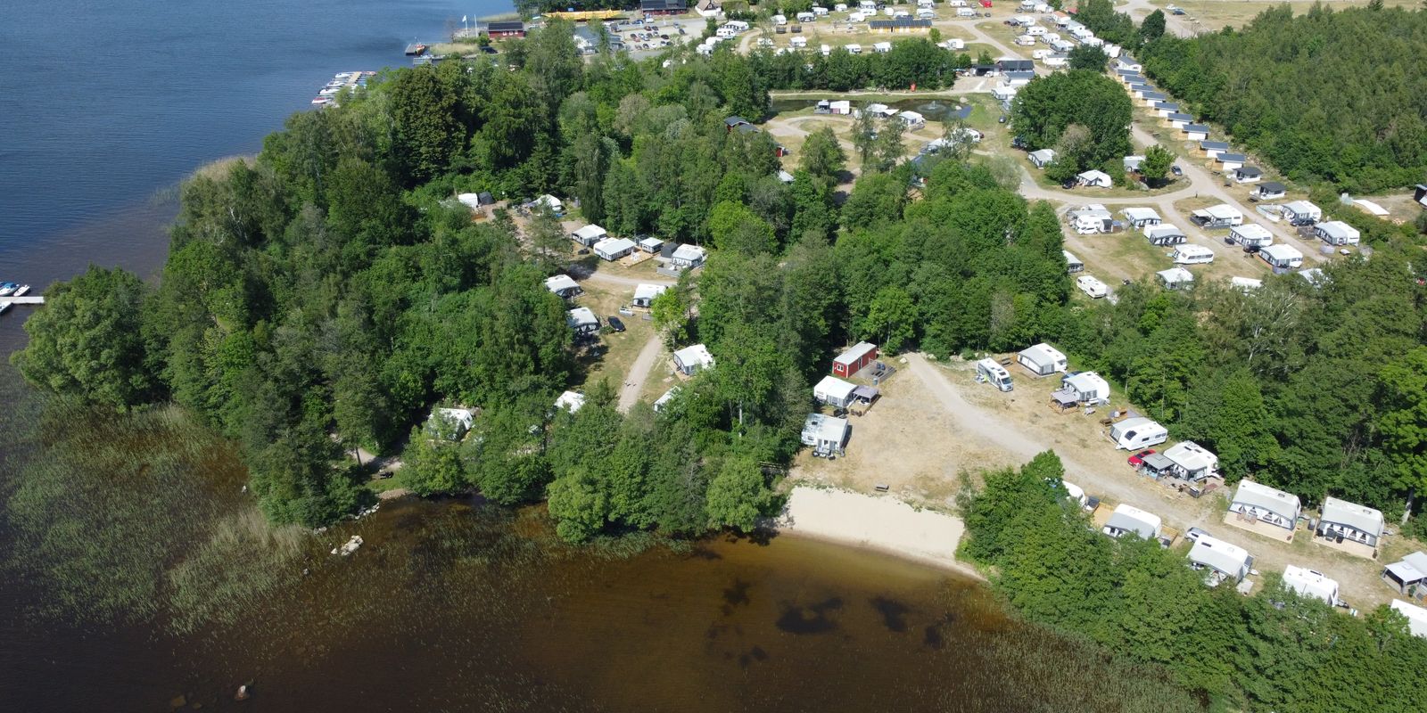 Aerial view of green forests, a lake and a camping area