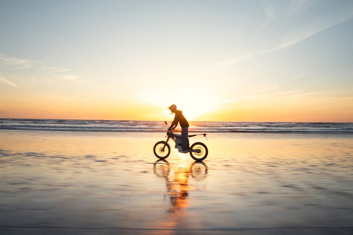 Man Riding Motocross on Beach at Sunset