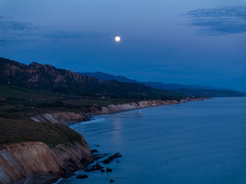 The moon rises over the ocean and the shoreline