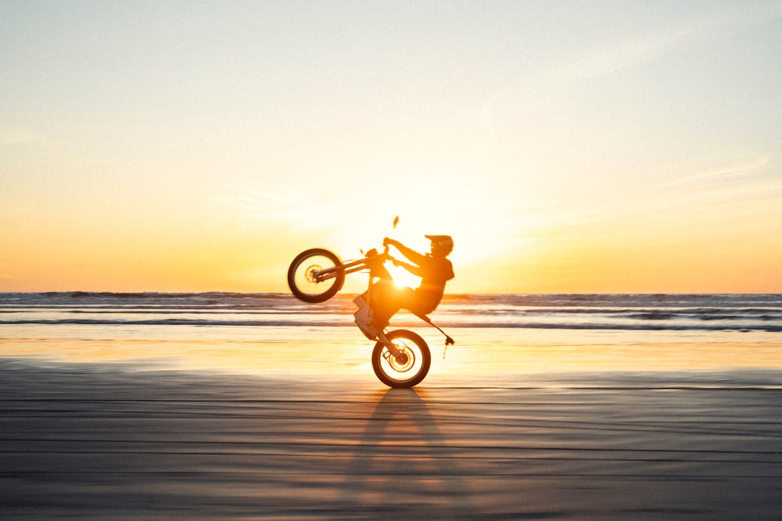 A person riding a motorcycle on the beach at sunset