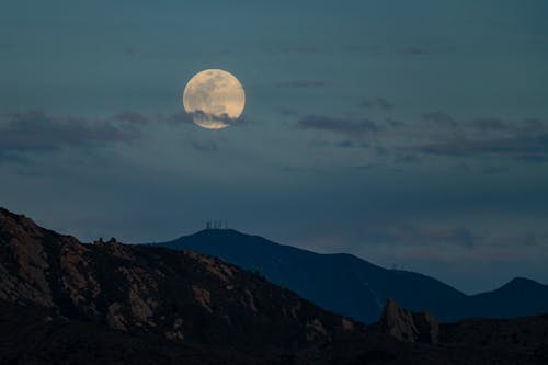 A full moon rises over a mountain range