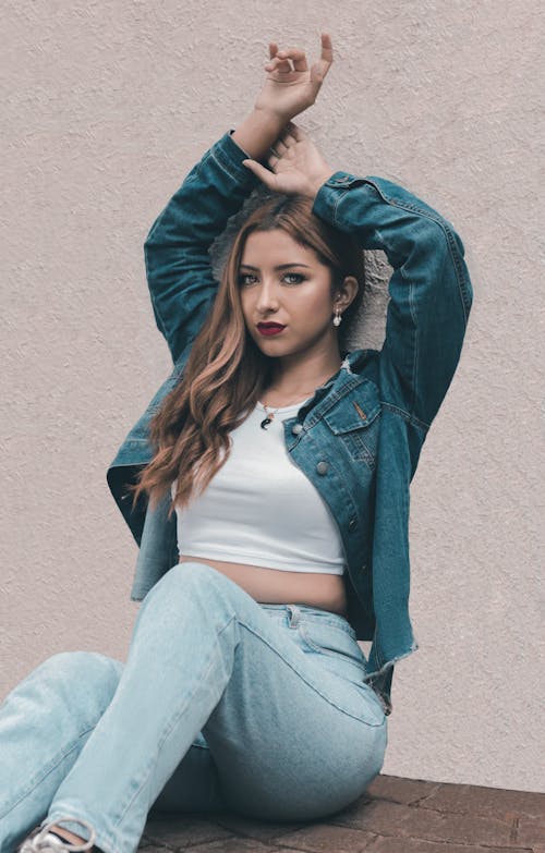 Woman in Jean Jacket Sitting with Arms Raised