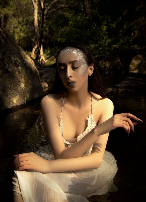 Free A serene portrait of a woman with closed eyes wearing a white dress in a forest. Stock Photo